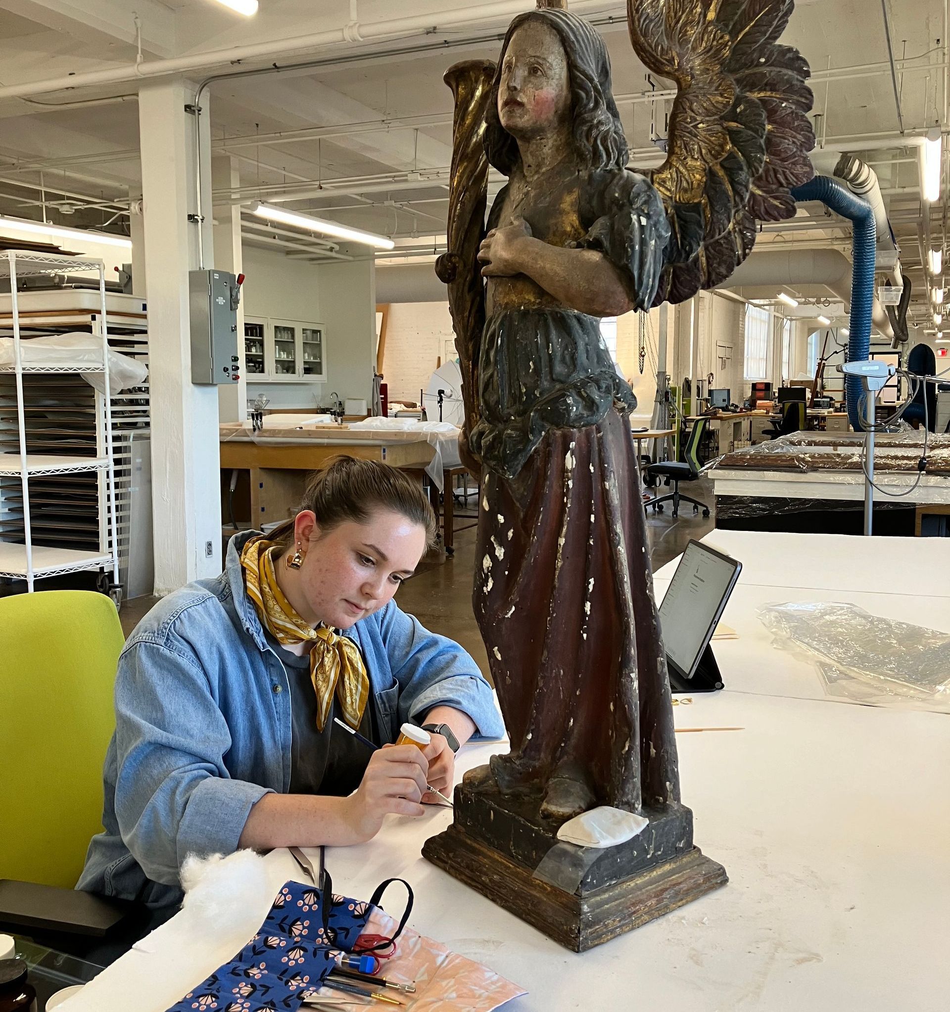 A woman is working on a statue of an angel