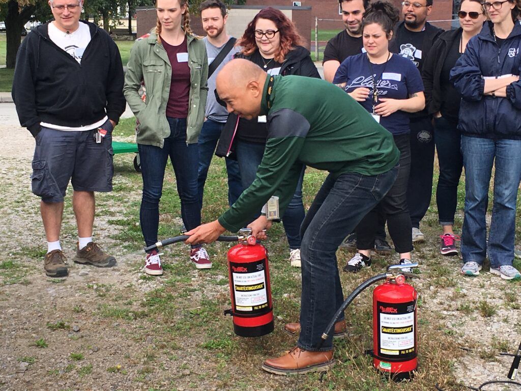 A man is using a fire extinguisher in front of a group of people.