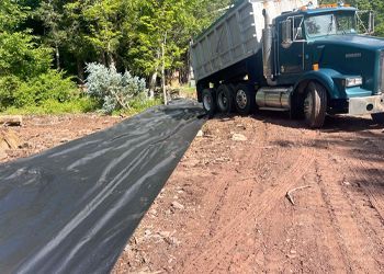 A dump truck is driving down a dirt road.