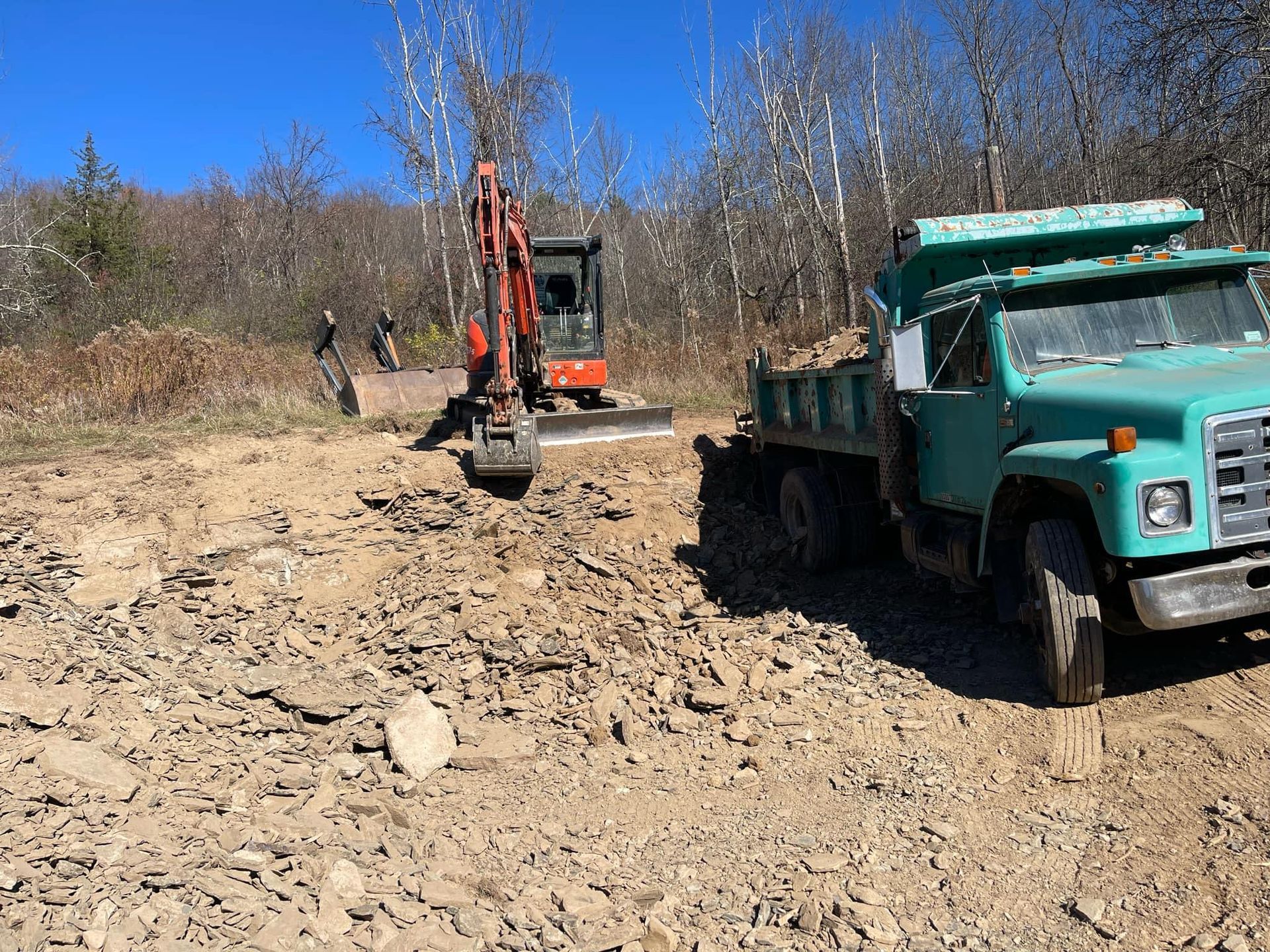 A green dump truck is parked next to an excavator