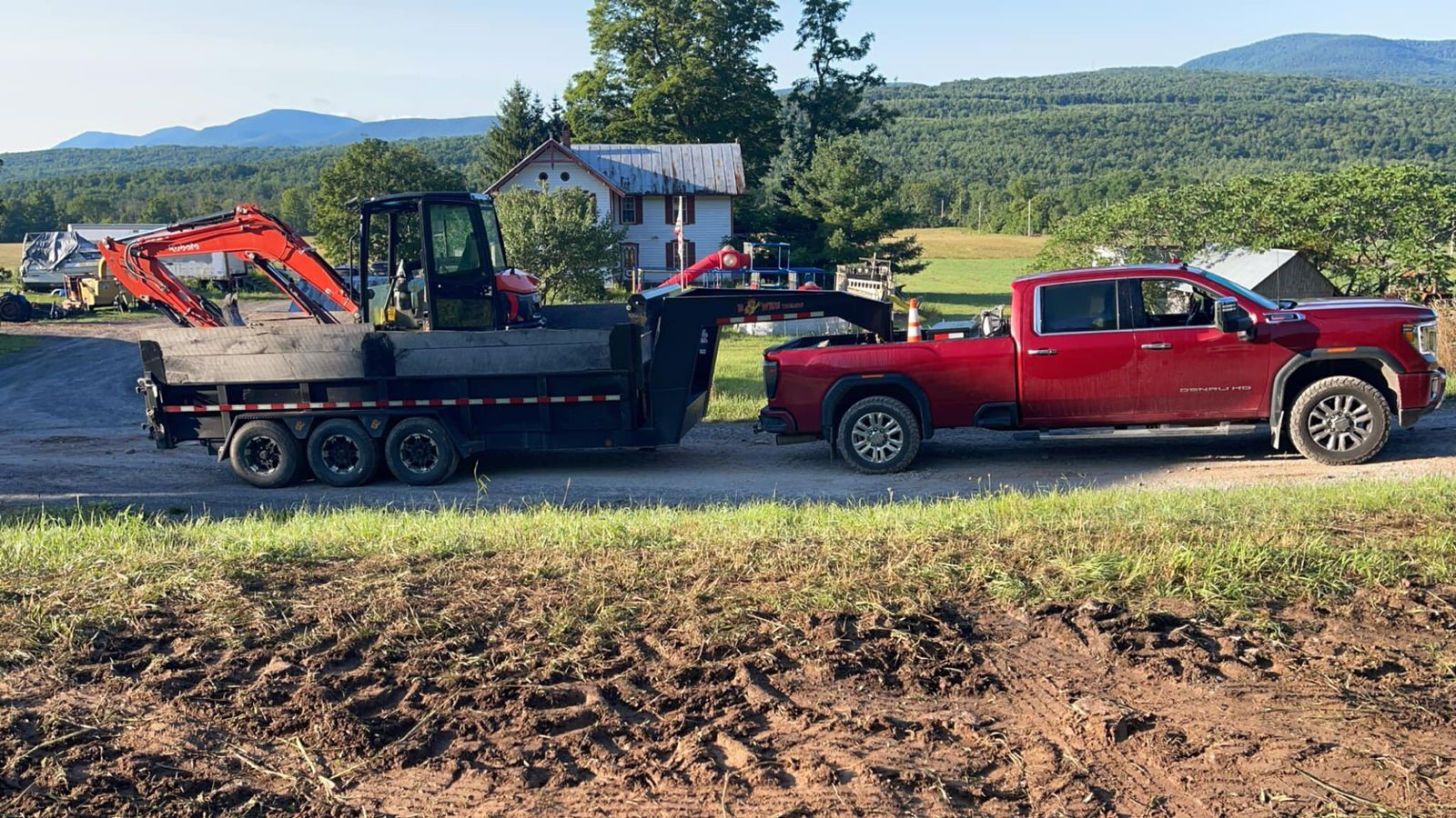 A red truck is pulling a trailer with an excavator on it.