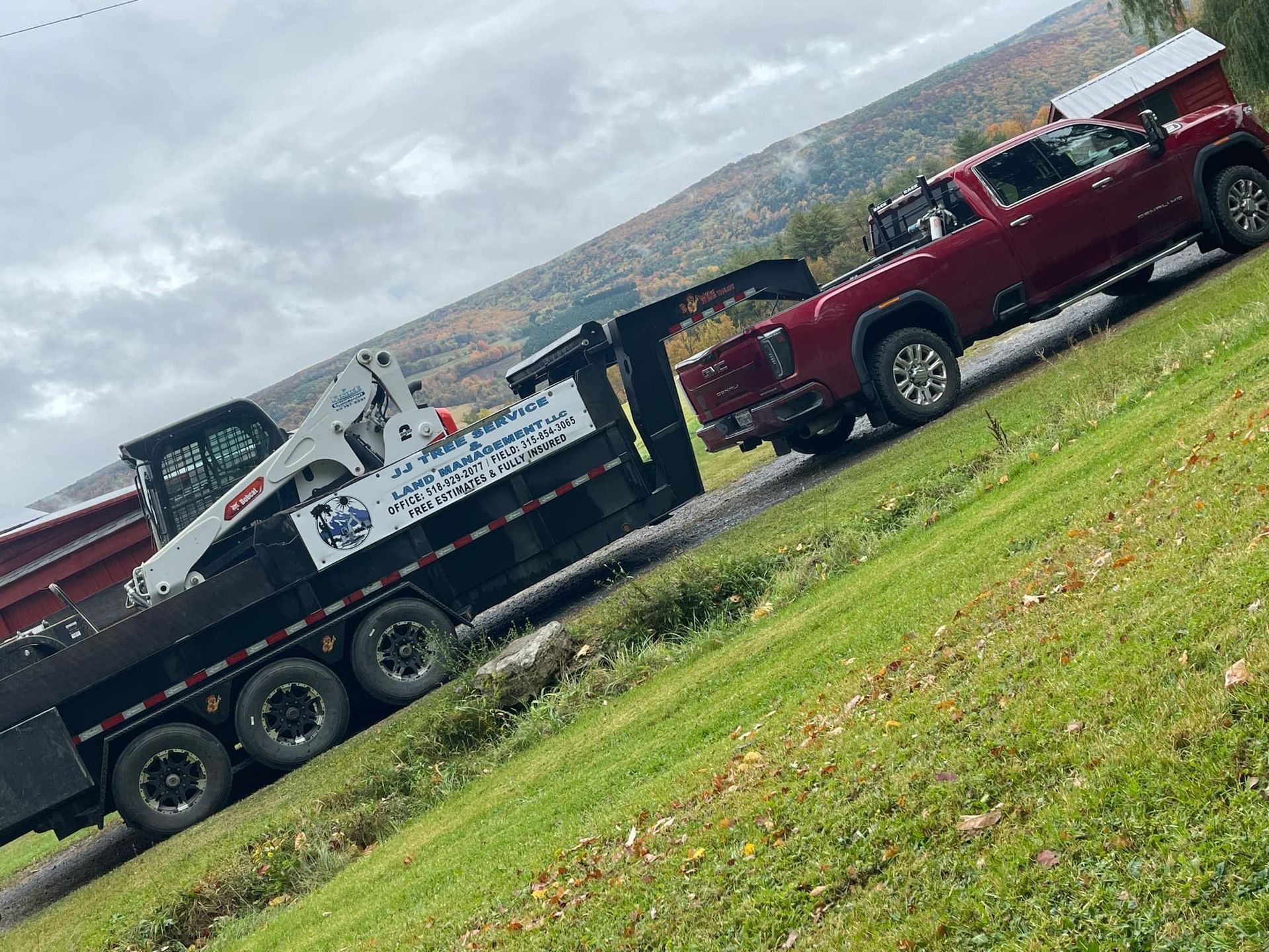A red truck is towing a trailer with a bulldozer on it.