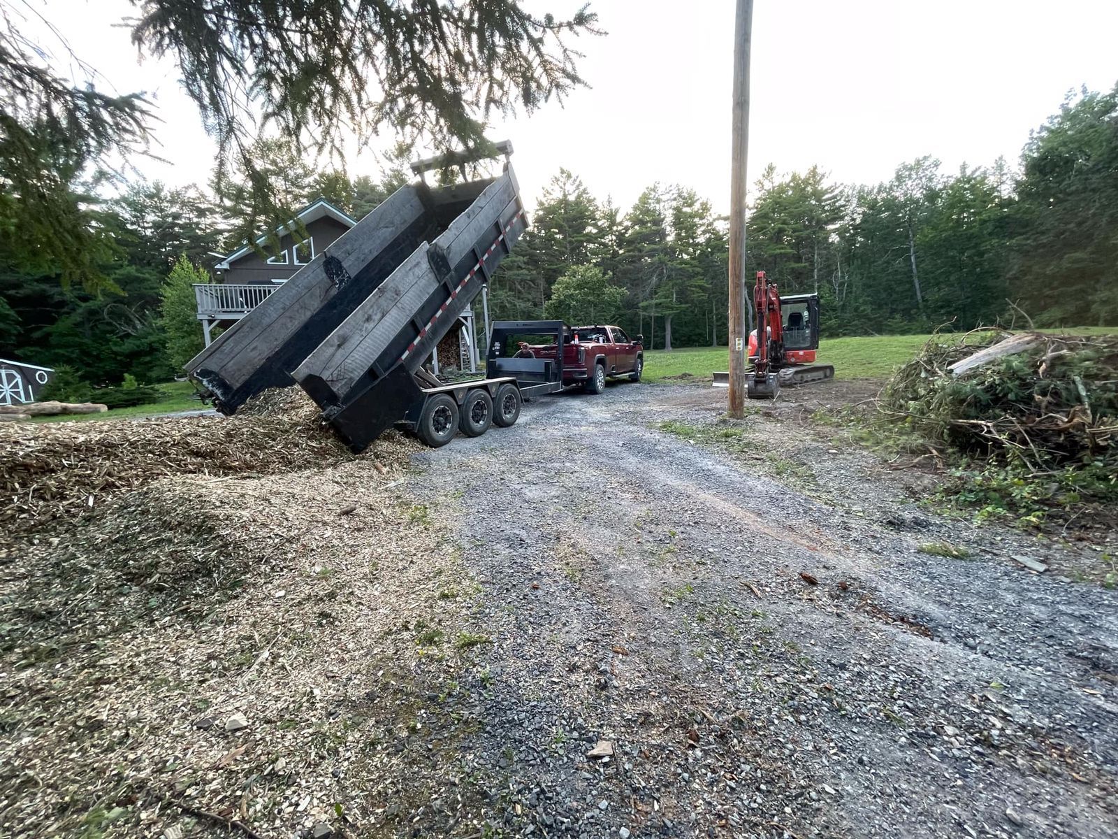 A dump truck is sitting on the side of a gravel road.