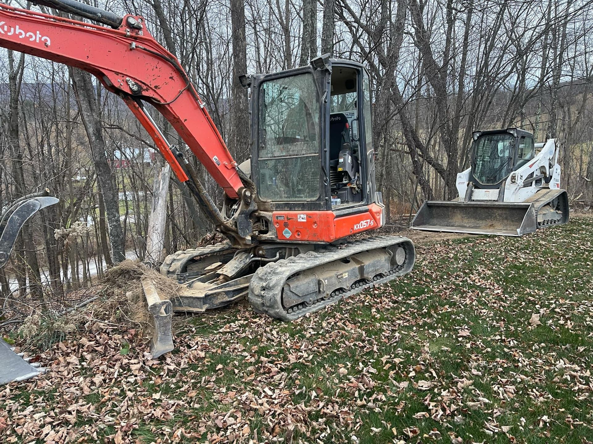 A red excavator and a white bulldozer are parked in a field.