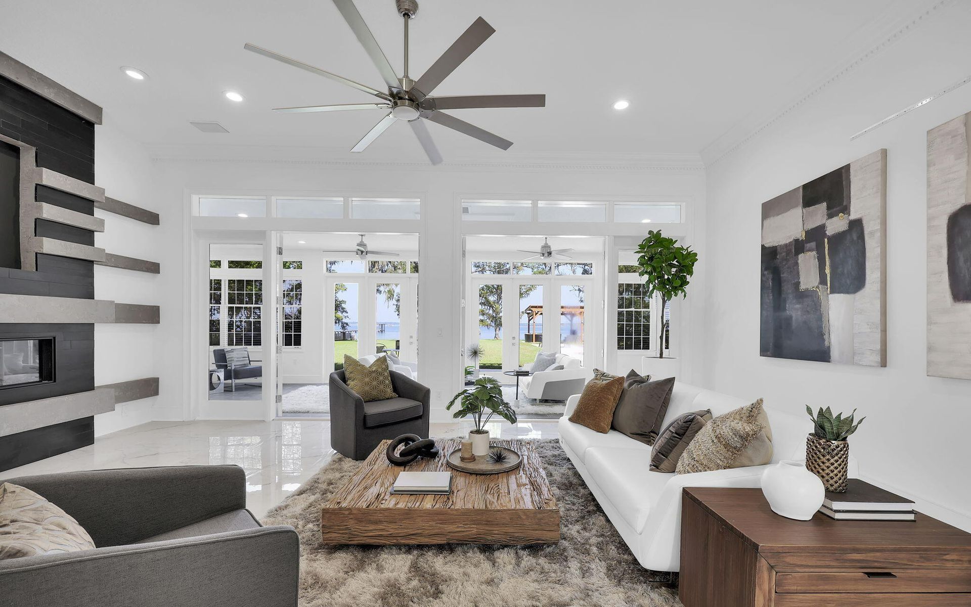 A living room with a couch , chairs , coffee table and ceiling fan.