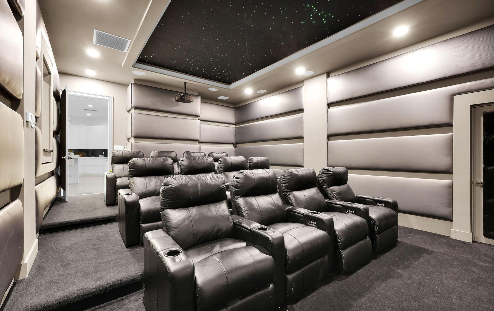 A home theater with black leather seats and a starry ceiling