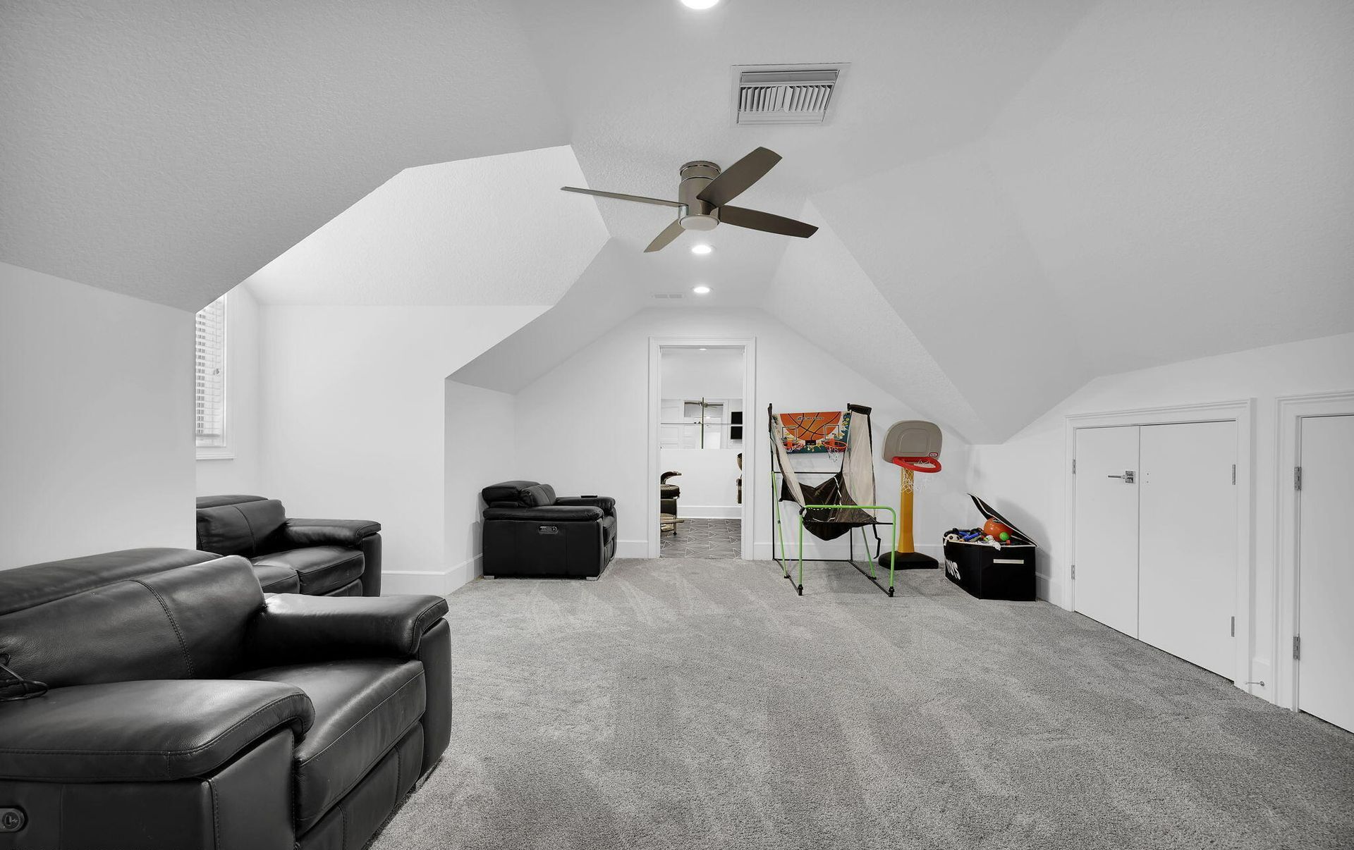 A living room with a couch , chairs , and a ceiling fan.