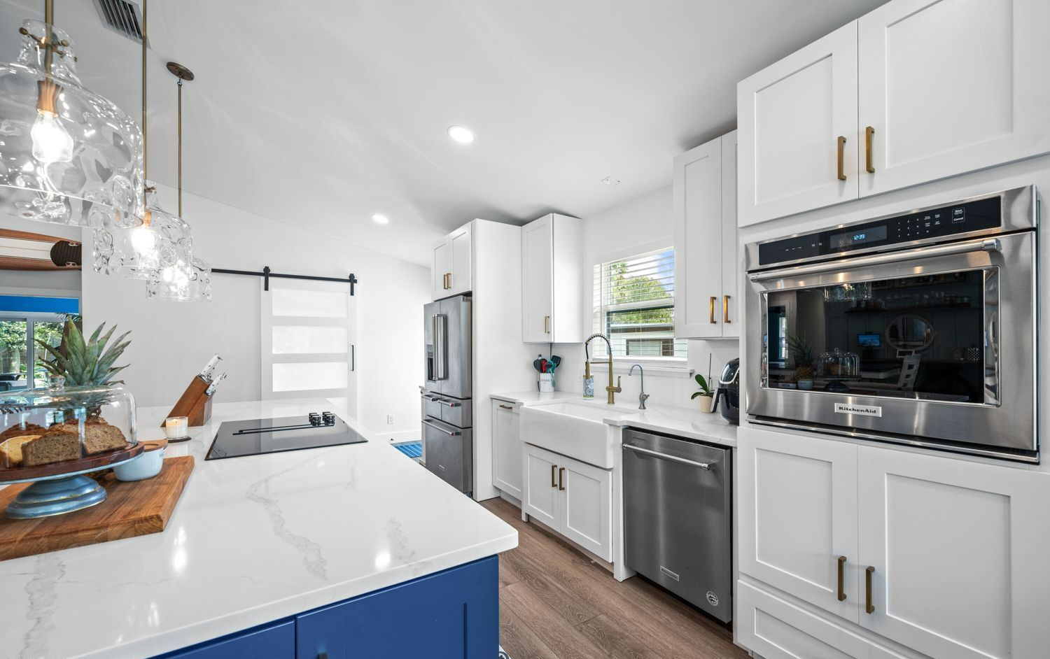 A kitchen with white cabinets and blue cabinets and stainless steel appliances.