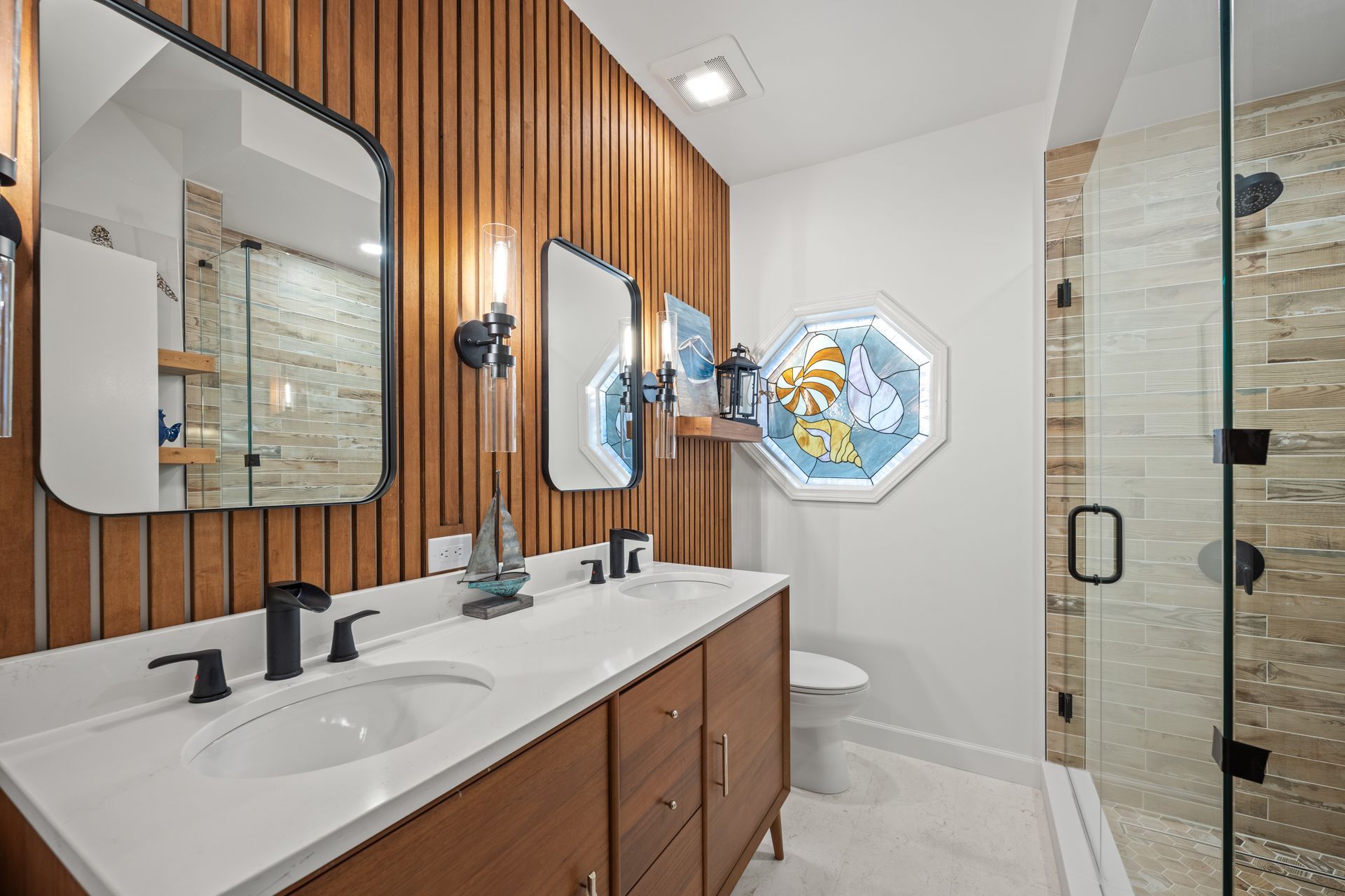 A bathroom with two sinks , a toilet and a shower.