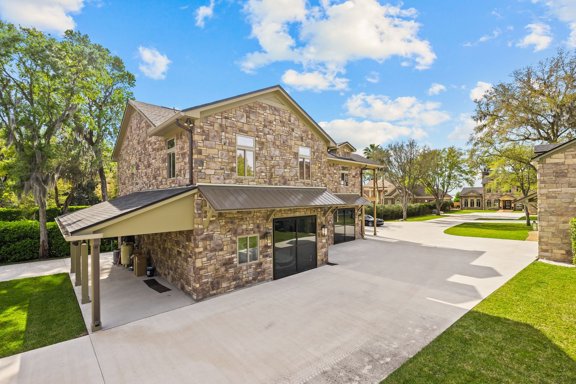 A large stone house with a garage and a driveway in front of it.