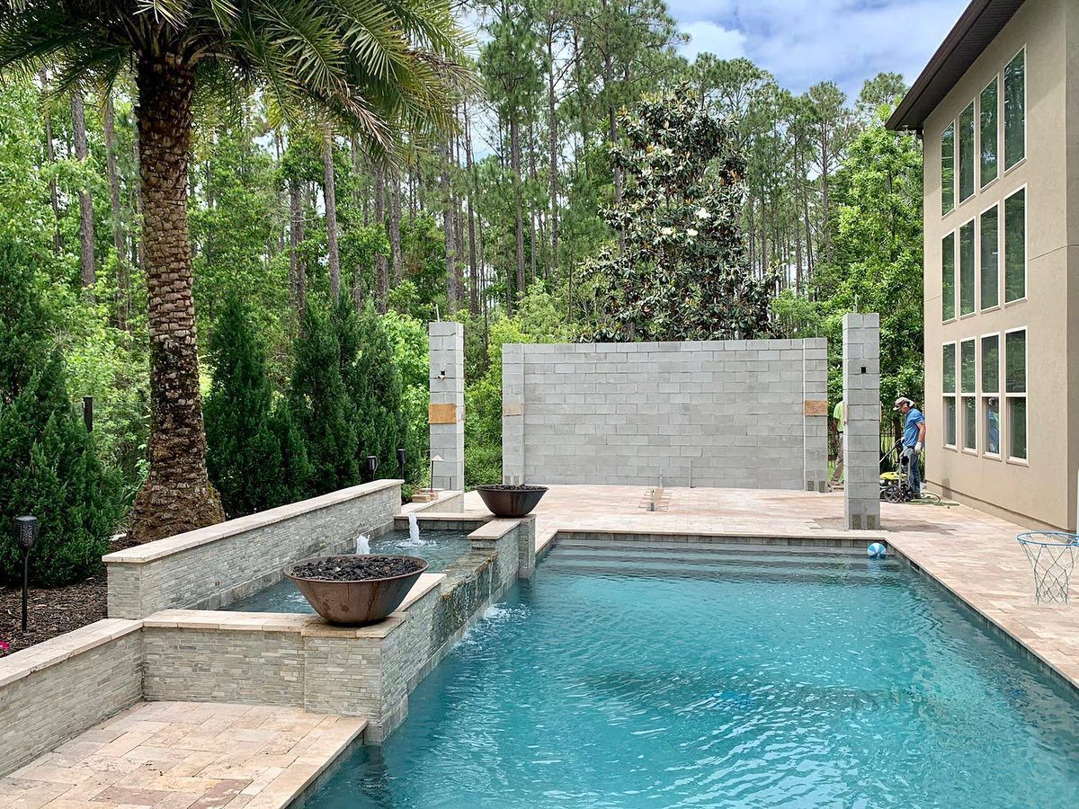 There is a large swimming pool in the backyard of a house.
