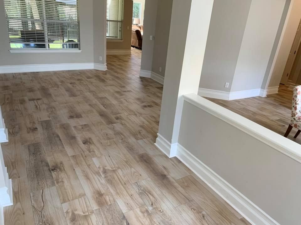 A hallway in a house with a wooden floor and a window.