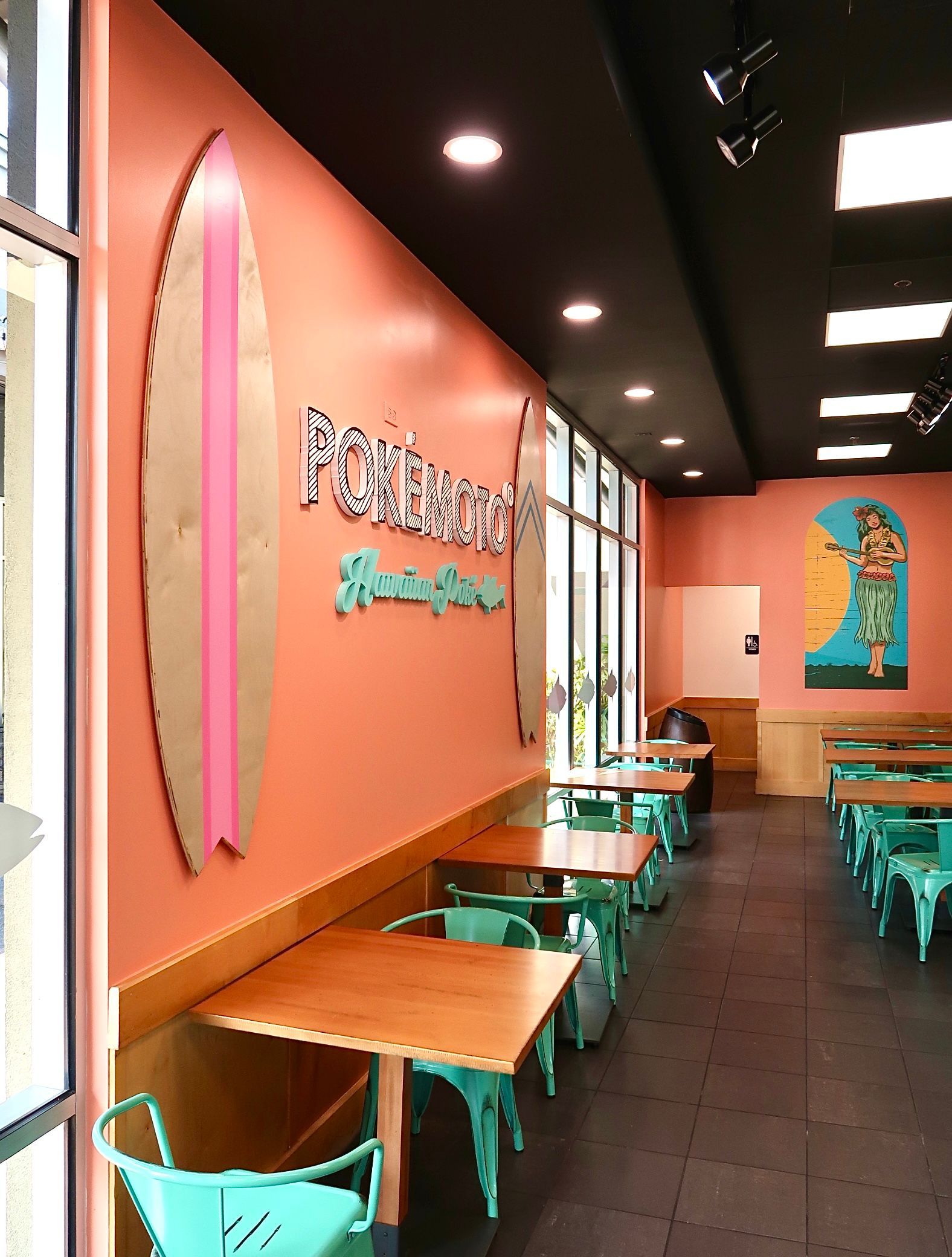 A restaurant with tables and chairs and a surfboard on the wall