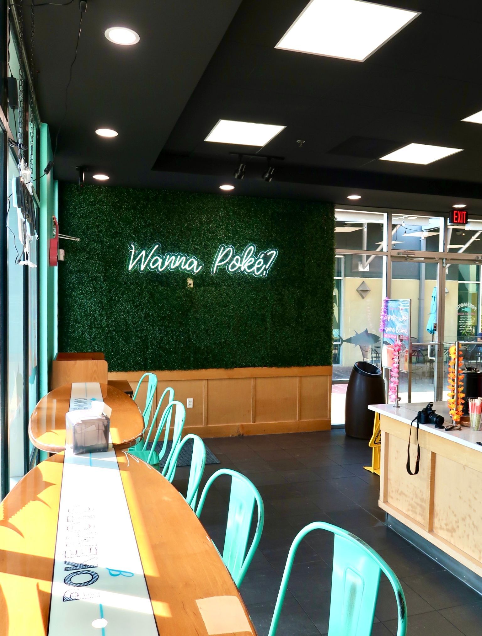 A restaurant with a neon sign that says wanna poke