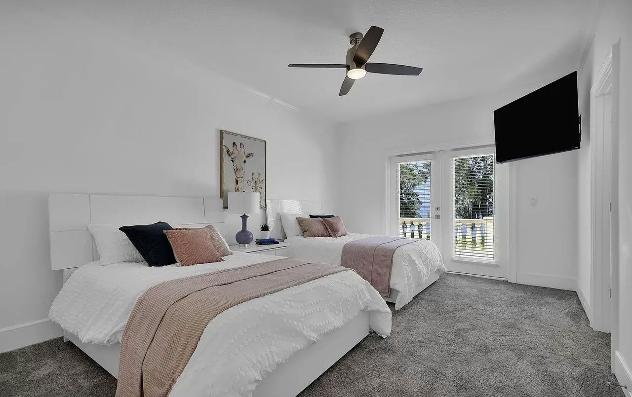 A bedroom with two beds , a television and a ceiling fan.
