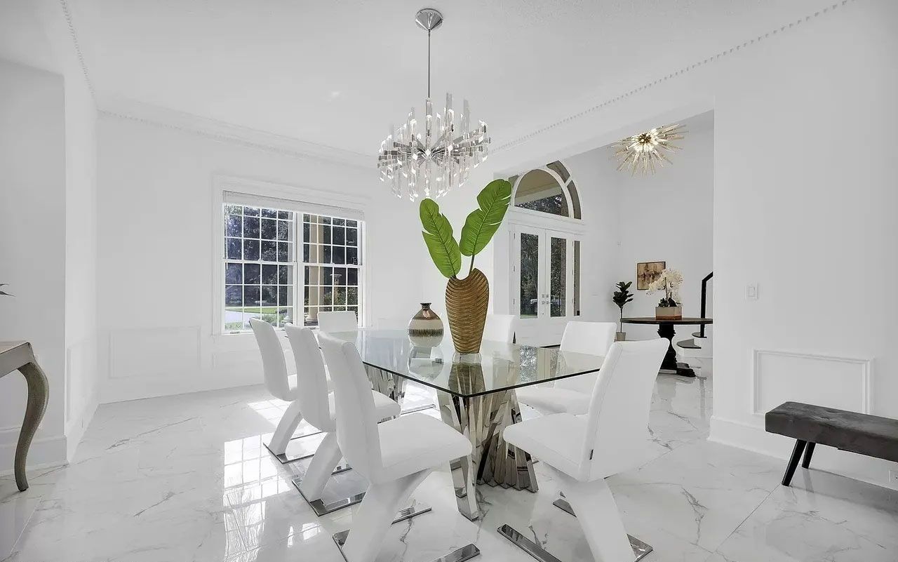 A dining room with a glass table and chairs and a chandelier.