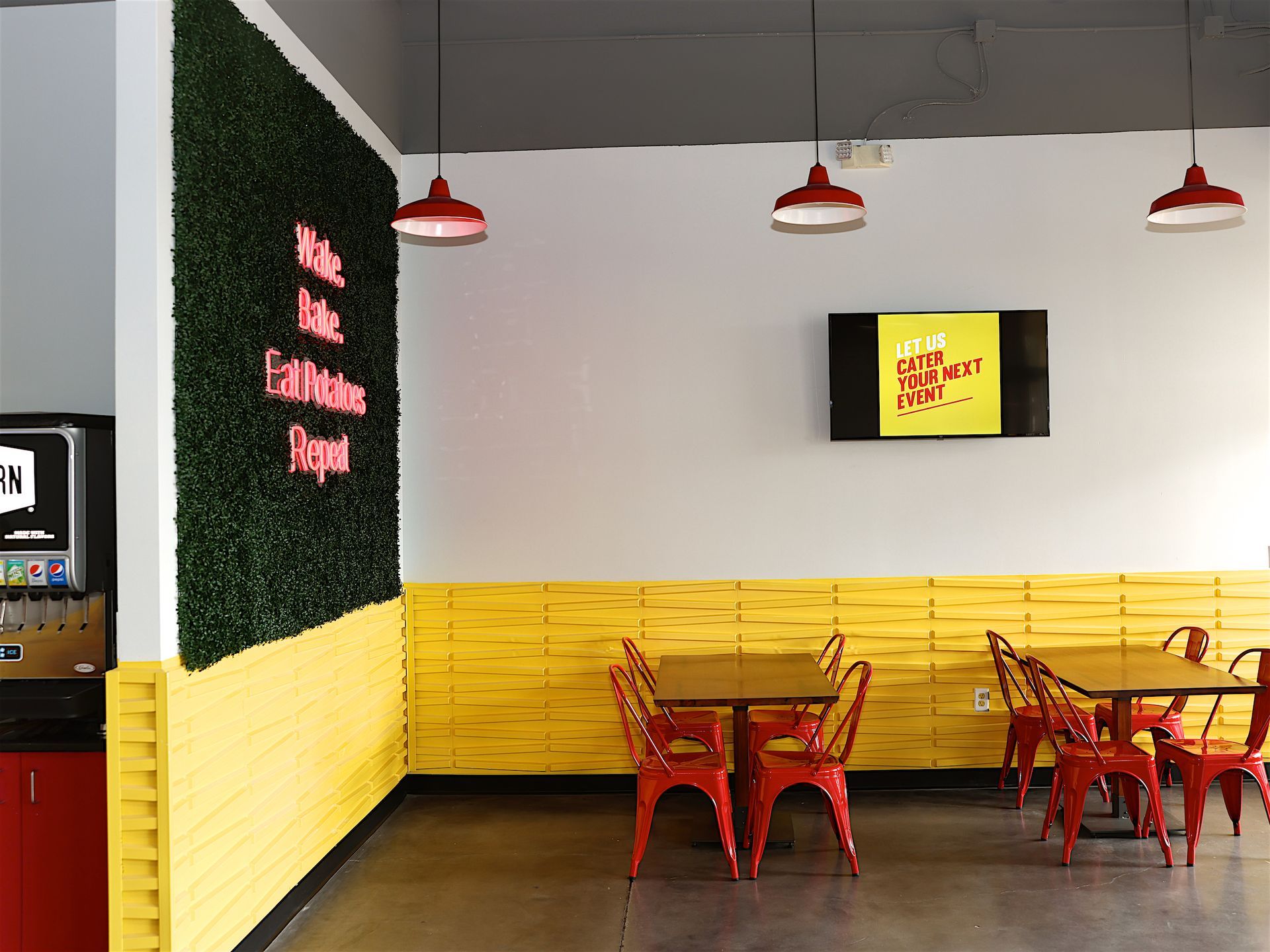 A restaurant with tables and chairs and a neon sign on the wall.