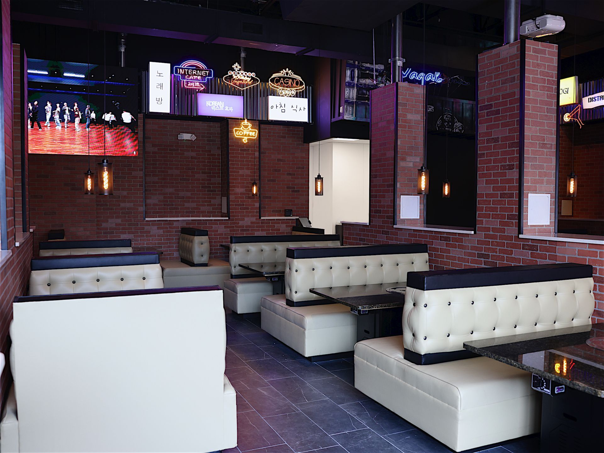 A restaurant with tables and benches and a brick wall.