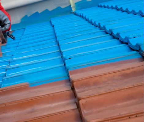 A person is painting a roof with blue paint.