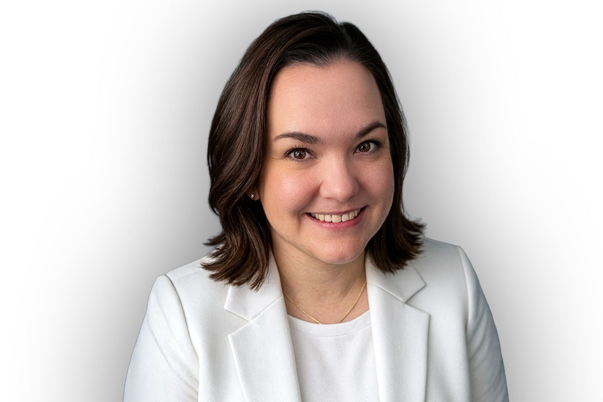 Woman in white blazer smiling, headshot.