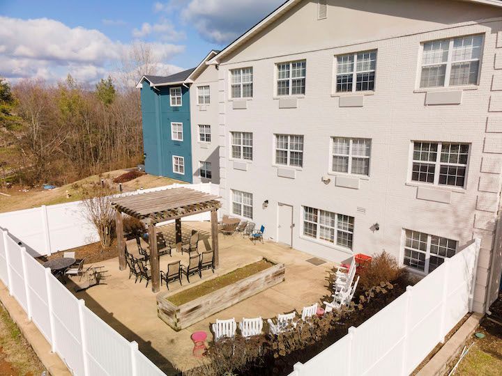 An aerial view of a large apartment building with a patio area surrounded by a white fence.