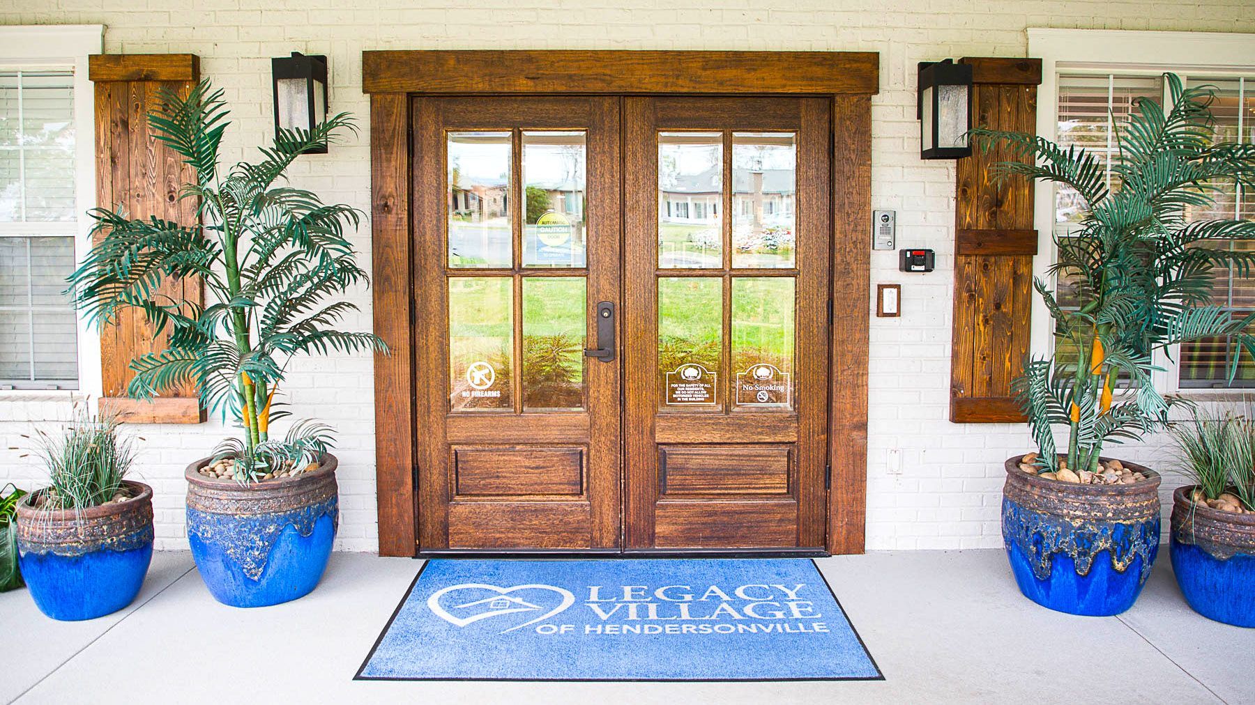 A wooden door with blue potted plants in front of it.