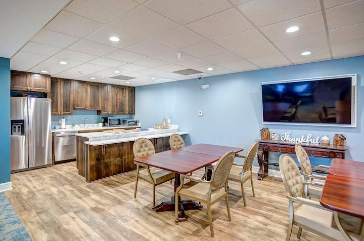 A dining room with tables and chairs and a large flat screen tv.