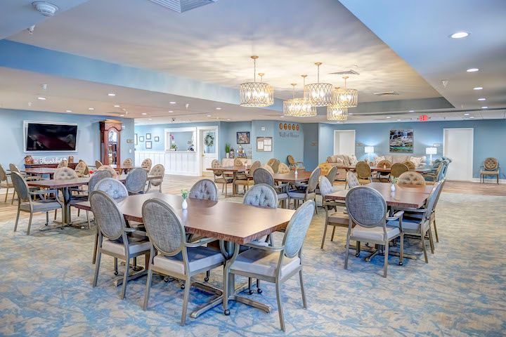 A large dining room with tables and chairs in a nursing home.