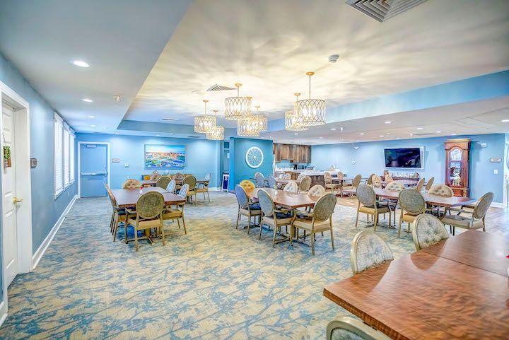 A large dining room with tables and chairs in a nursing home.