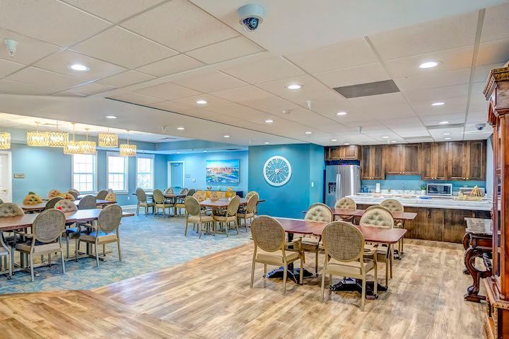 A large dining room with tables and chairs in a nursing home.