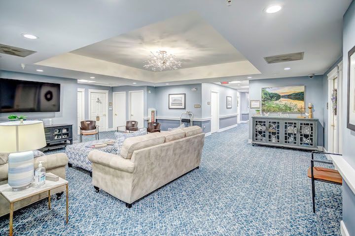 A living room with a couch , chairs , and a flat screen tv.