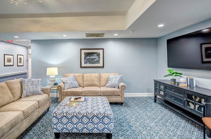 A living room with a couch , ottoman , table and television.