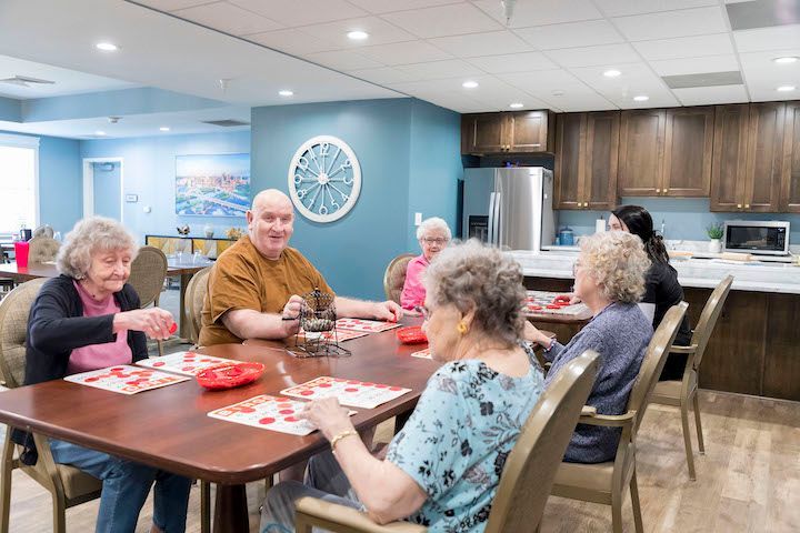 A group of elderly people are sitting around a table playing cards.