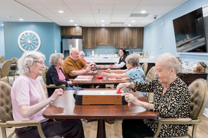 A group of elderly people are sitting at tables playing cards.