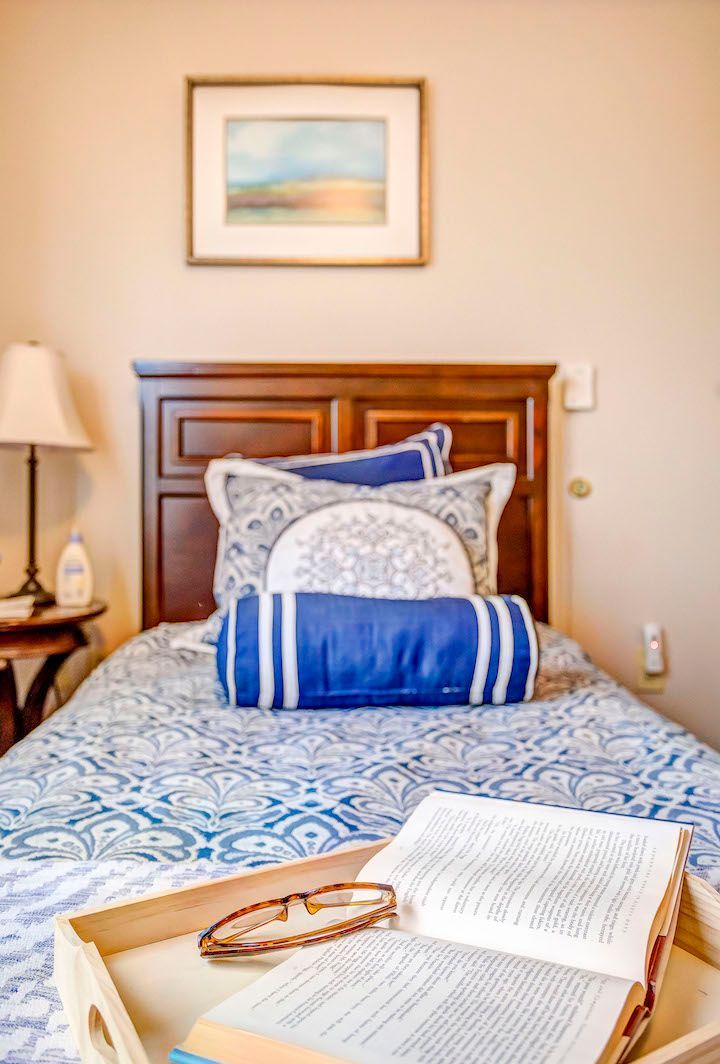 A bedroom with a bed , a tray with a book and glasses on it.