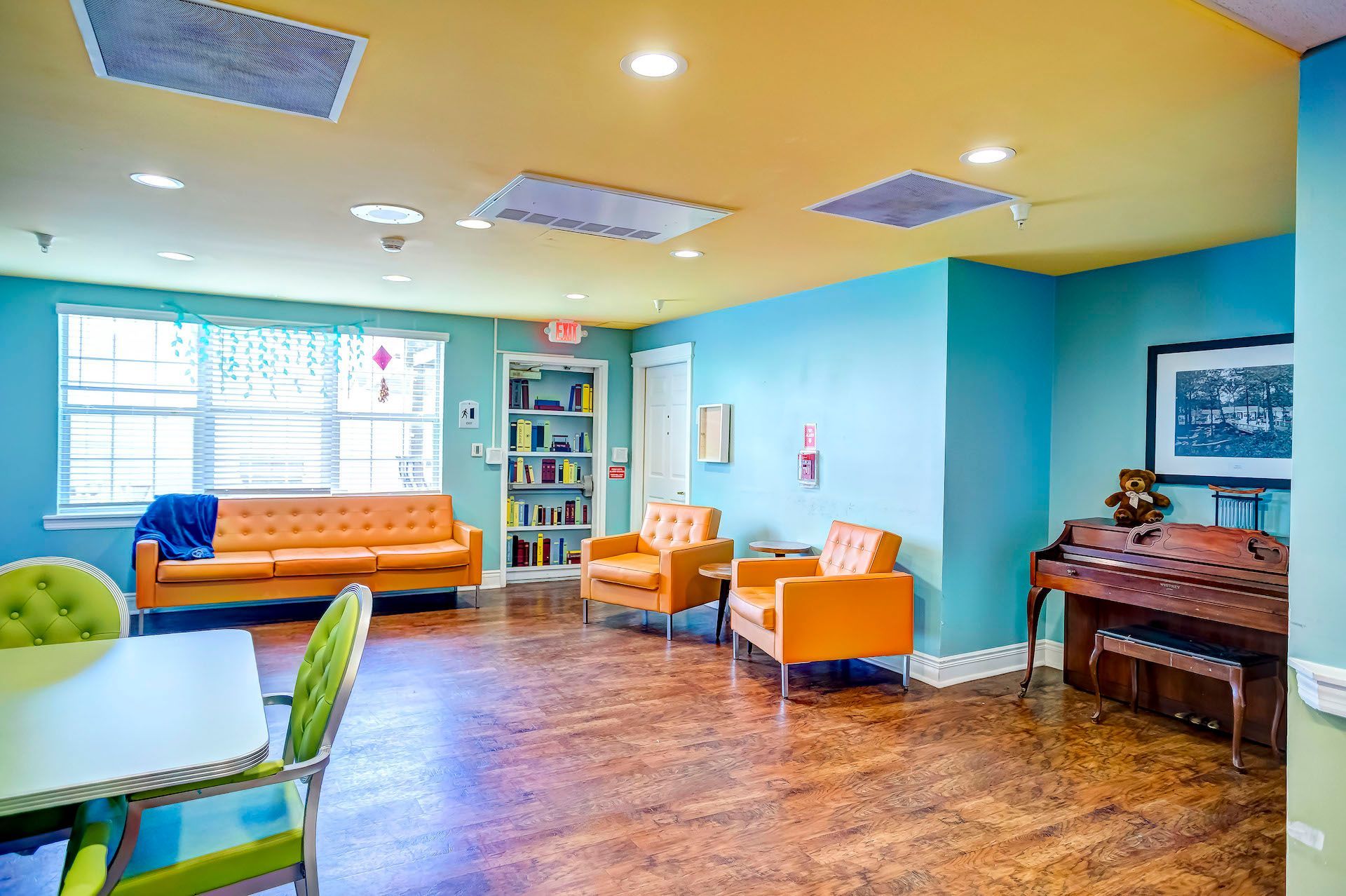 A living room with a couch , chairs , tables and a piano.