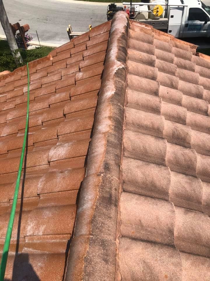 A close-up shows a weathered, terracotta tile roof with a green hose running along the side.