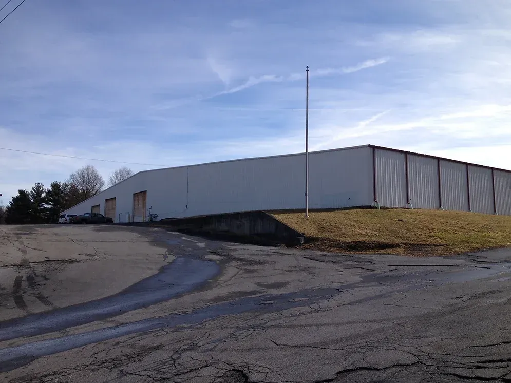 A large white building is sitting on top of a grassy hill.