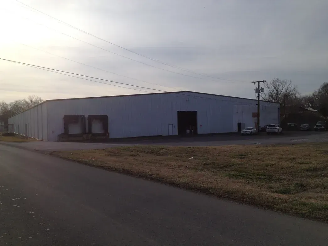 A large white building is sitting on the side of a road.