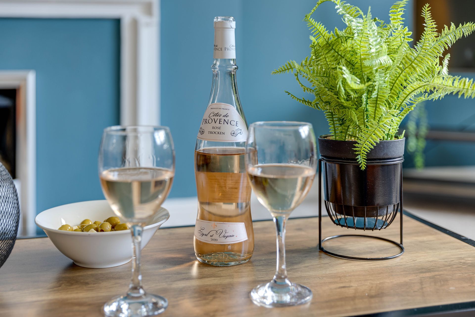 A bottle of wine and two glasses of wine are on a table.