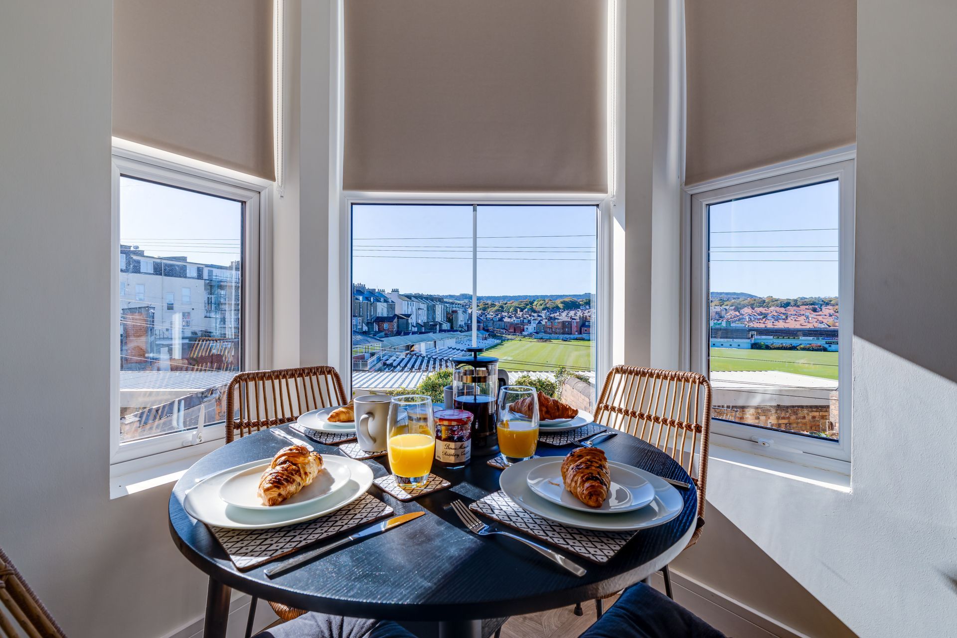A table with plates of food and drinks on it in front of a window.