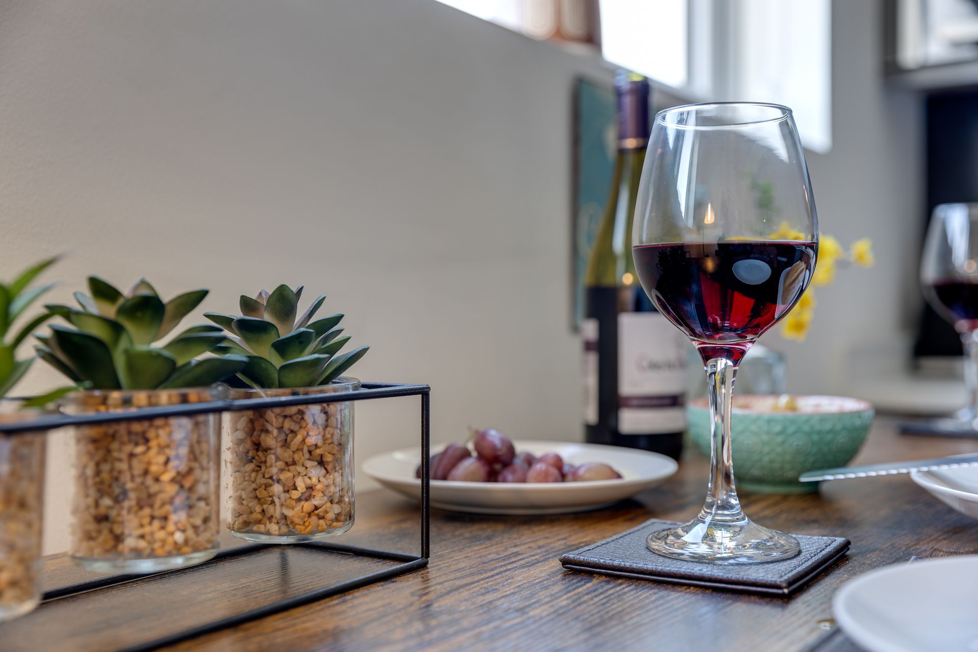 A glass of wine is sitting on a wooden table next to a bottle of wine.