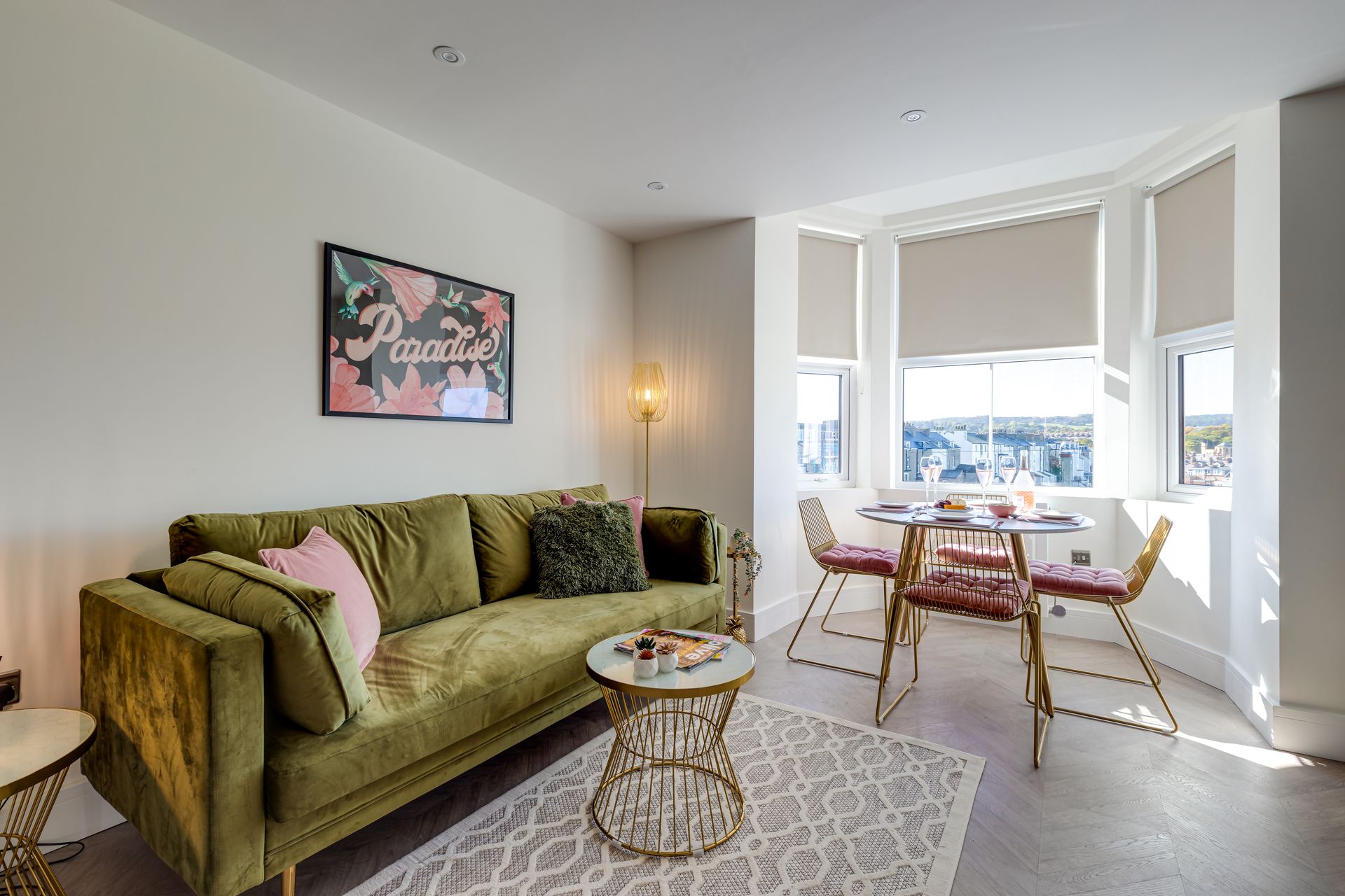 A living room with a green couch , table and chairs.