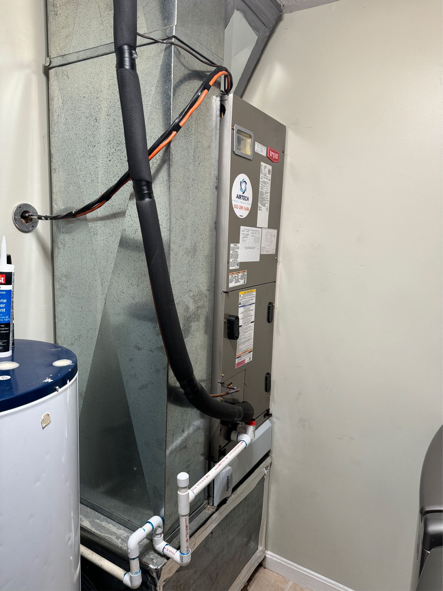 HVAC unit in a utility room next to a water heater. Ductwork visible.