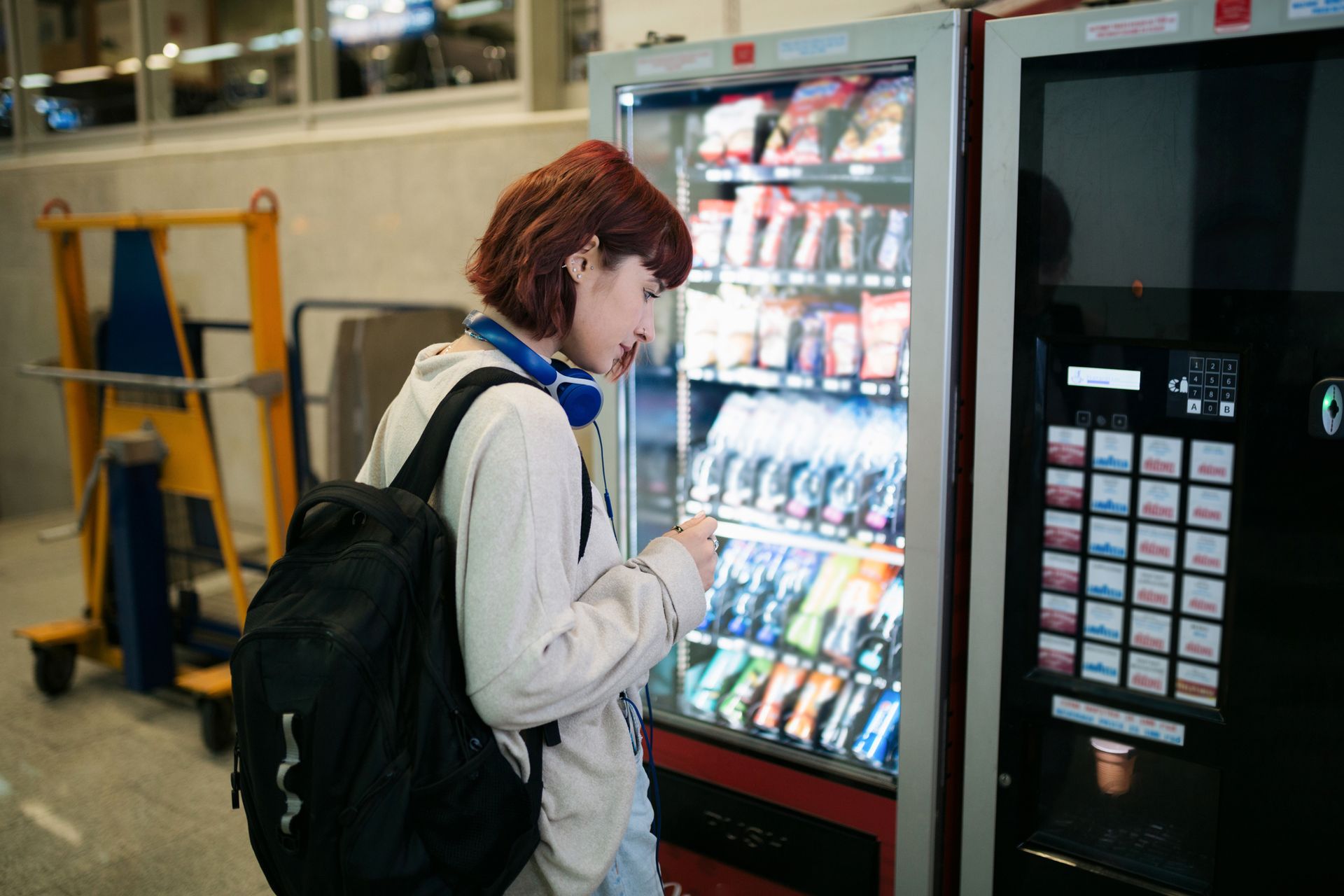 A Woman Is Using A Vending Machine In A Store.