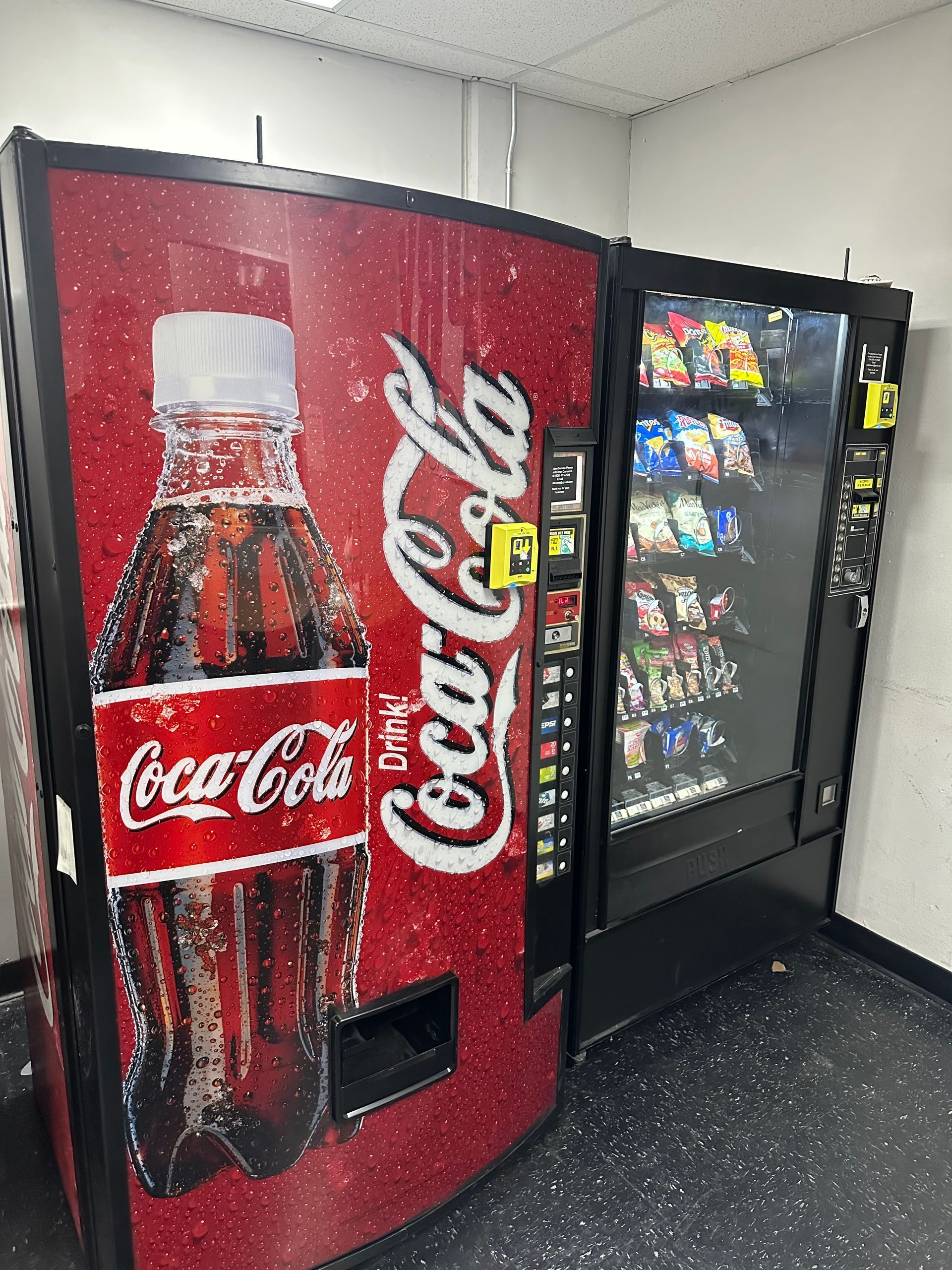 A Soft Drinks Vending Machine Is Next To A Snack Machine.