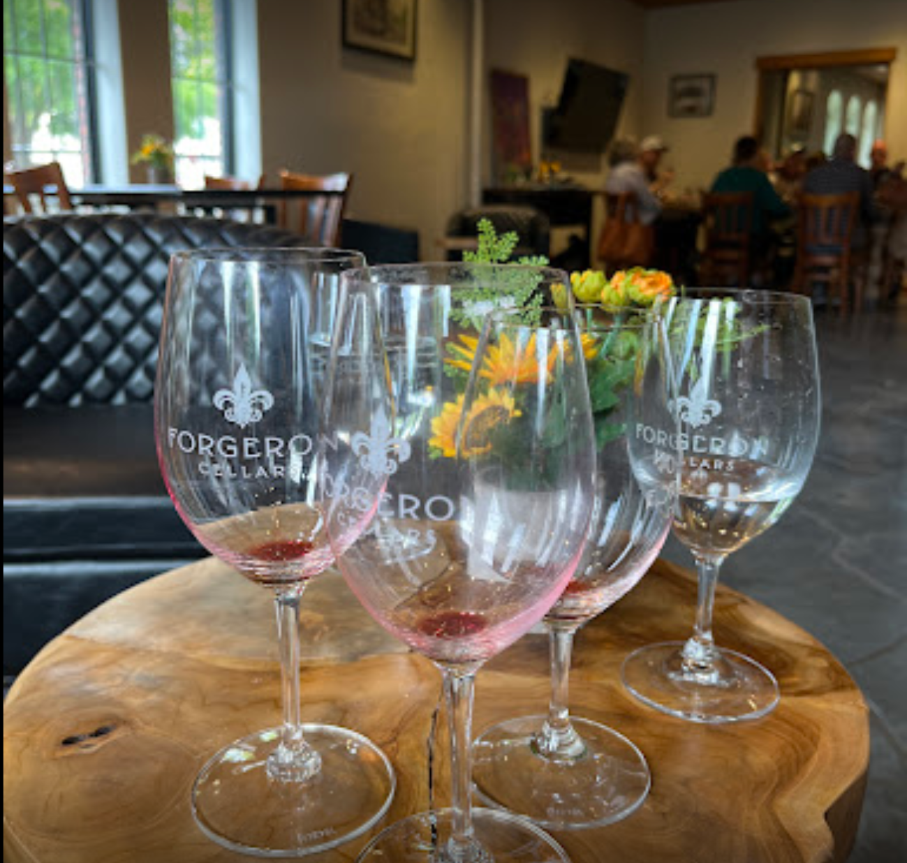 Four wine glasses are sitting on a wooden table and one of them says jorgero cellars