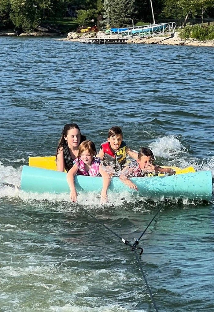 A group of children are riding on a tube in the water.