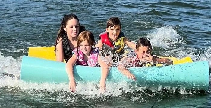 A group of children are floating on a raft in the water.