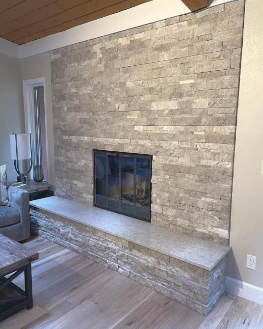 A living room with a fireplace and a brick wall.